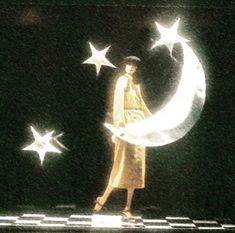 a woman standing on top of a moon and stars