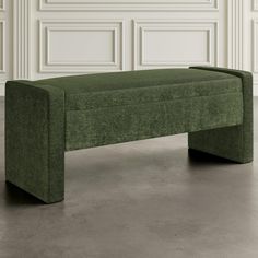 a green bench sitting on top of a cement floor next to a white paneled wall