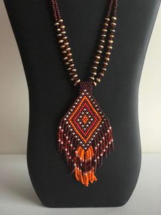 The pendant is made of brown, cream, orange and red seed beads with small orange crystals in the fringes.  The pendant is attached to dzi agate stones and  is finished with a black chain and S hook closure.  I can adjust the length of the chain if you wish. "Dzi" agate is made to resemble beads first found in India between 1000 and 2000 BCE.  These reproductions are designed in the traditional color pattern and finish of the original Dzi beads.Authentic Dzi beads were used in ancient times in India, Tibet and other Asian countries, and those that still exist today have been passed down for generations.  The original stones were often used as protective amulets and are usually scarred or pitted in places where they were ground off for use in traditional medicines. Bohemian Orange Hand-strung Necklace, Bohemian Orange Beaded Necklaces For Jewelry Making, Orange Bohemian Beaded Necklaces For Jewelry Making, Bohemian Hand-strung Orange Beads, Hand-strung Orange Bohemian Beads, Orange Bohemian Hand-strung Beaded Necklace, Handmade Southwestern Orange Beaded Necklaces, Handmade Orange Southwestern Necklace, Artisan Brown Handwoven Necklace