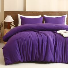 a bed with purple sheets and pillows in a room