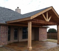 a covered patio in front of a brick house