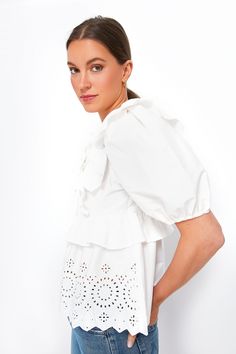 Moon River is an L.A.-based apparel company that makes easy, trendy pieces for day or night.Somehow both sweet and sassy, the White Ruffle Eyelet Top does it all. Short puff sleeves, ruffle features, and eyelet detailing on the hem make for a charming silhouette that's contrasted by the slightly sultry set of triple neckties with cutouts that line the bodice. Perfect for spring and summer dressing we are pairing this fun and feminine number with denim of all colors and sandals for a warm-weather Flirty White Ruffled Tops, Flirty Ruffled Blouse For Brunch, Flirty Ruffled Blouse For Day Out, Chic Tops With Broderie Anglaise And Ruffled Collar, Flirty Short Sleeve Blouse With Ruffles, Summer Dressing, Moon River, Eyelet Top, Scalloped Hem