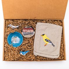 an open box with various items in it including a towel, bowl and bird figurines