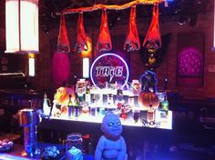 a bar with an assortment of liquor bottles and glasses on the bar top, next to a baby doll