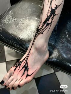 a woman's foot with black ink and vines on the side of her leg