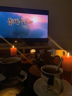 a harry potter movie is on the screen in front of some coffee cups and saucers