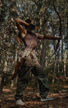 a woman is standing in the woods with a bow and arrow on her back,