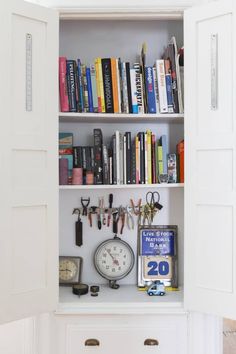 a bookshelf filled with lots of books next to a clock and other items