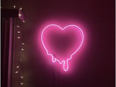 a heart shaped neon sign hanging from the side of a wall