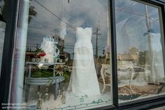 a wedding dress is in the window of a clothing store with other items behind it