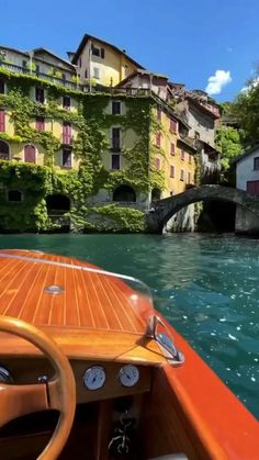 a boat traveling down a river next to a lush green hillside covered in greenery