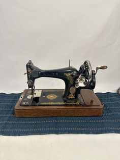 an old sewing machine sitting on top of a blue table cloth with other items around it