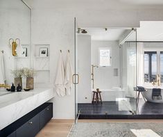 a bathroom with marble counter tops and white walls, along with gold accents on the shower