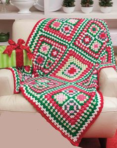 a white chair with a red and green afghan on it's back in front of a christmas tree