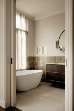 a bathroom with a bathtub, sink and mirror on the wall next to it