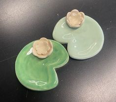 two green plates with flowers on them sitting next to each other, one has a flower in the middle