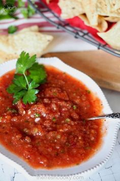 a bowl of salsa with tortilla chips and cilantro on the side