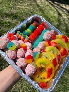 a person holding a tray full of fruit covered in sprinkles