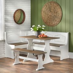 a table with two benches and some fruit on the plate next to it, in front of a green painted wall