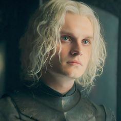 a man with blonde hair and blue eyes in a suit of armor looking at the camera