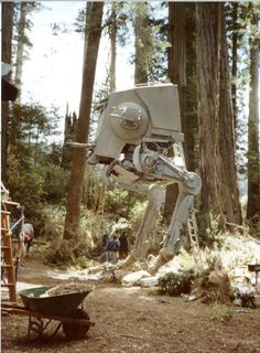 a star wars at - at in the woods with people standing around and looking at it