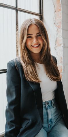 a woman sitting in front of a window smiling