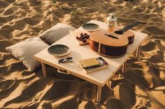 a table with a guitar on it in the sand