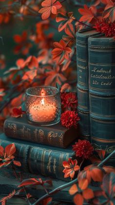 two books and a candle on top of each other with red flowers in the background