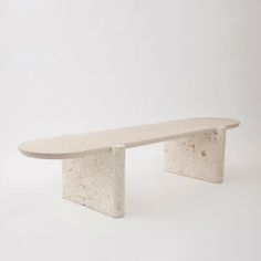 a white bench sitting on top of a wooden table next to a white wall and floor