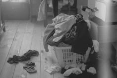 a pile of clothes sitting on top of a wooden floor next to a laundry basket