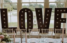 the word love is spelled out in front of chairs and table settings for a wedding reception