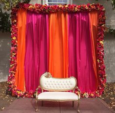 an orange and pink backdrop with a white bench in front of it on the sidewalk