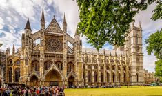 people are standing in front of a large building with many spires on it's sides