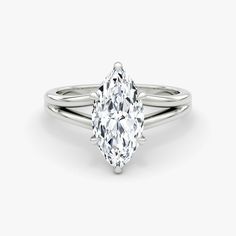 a white gold ring with a pear shaped diamond in the center, on a plain surface