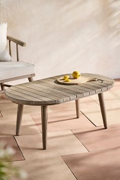 a coffee table with two lemons on it in front of a chair and wall