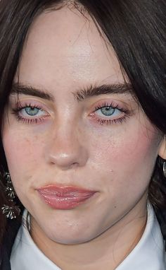 a woman with freckled hair and blue eyes wearing a white collared shirt