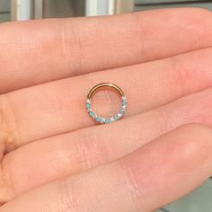 a woman's hand holding a gold ring with blue stones on the inside of it