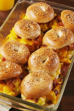 several bagels with cheese and bacon on them in a glass dish sitting on a wooden table