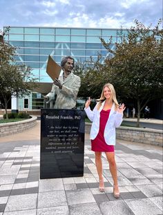 a woman standing next to a statue in front of a building