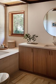 a bathroom with a sink, mirror and bathtub next to a window in the wall