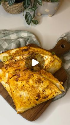 two pieces of pizza on a cutting board with a knife and potted plant in the background