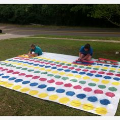 two children are playing on a large blanket in the grass