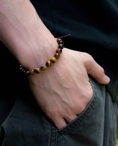 Handsome men's bracelet of natural Tiger's Eye strung on brown beading cord with adjustable draw string macrame closure.  The Tiger's Eye gemstones are 8mm smooth round stones of high quality in their natural dark and light brown coloring.  The bracelet is 7" in length adjustable up to 9".  This bracelet looks great with a suit or jeans.  Very versatile and layers will with other bracelets. Beading Cord, Tiger Eye Bracelet, Tigers Eye Gemstone, Eye Bracelet, Tiger's Eye, Handmade Bracelet, Bracelet Handmade, Adjustable Bracelet, Tiger Eye