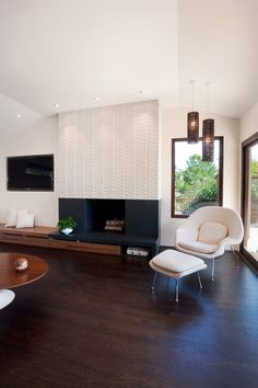 a large living room with wood flooring and white furniture in front of a flat screen tv mounted on the wall