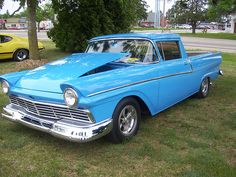 an old blue car is parked in the grass