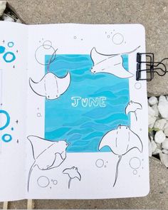 an open notebook with the words june written on it and dolphins swimming in the water