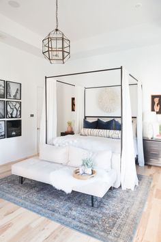 a white bed sitting on top of a wooden floor next to a living room filled with furniture