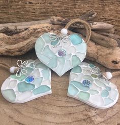 three heart shaped ornaments sitting on top of a piece of driftwood