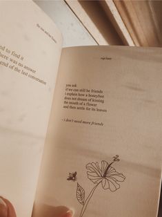 a person holding an open book with a flower on the page and a poem written in it