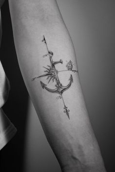 a black and white photo of a person with a tattoo on their arm holding an anchor